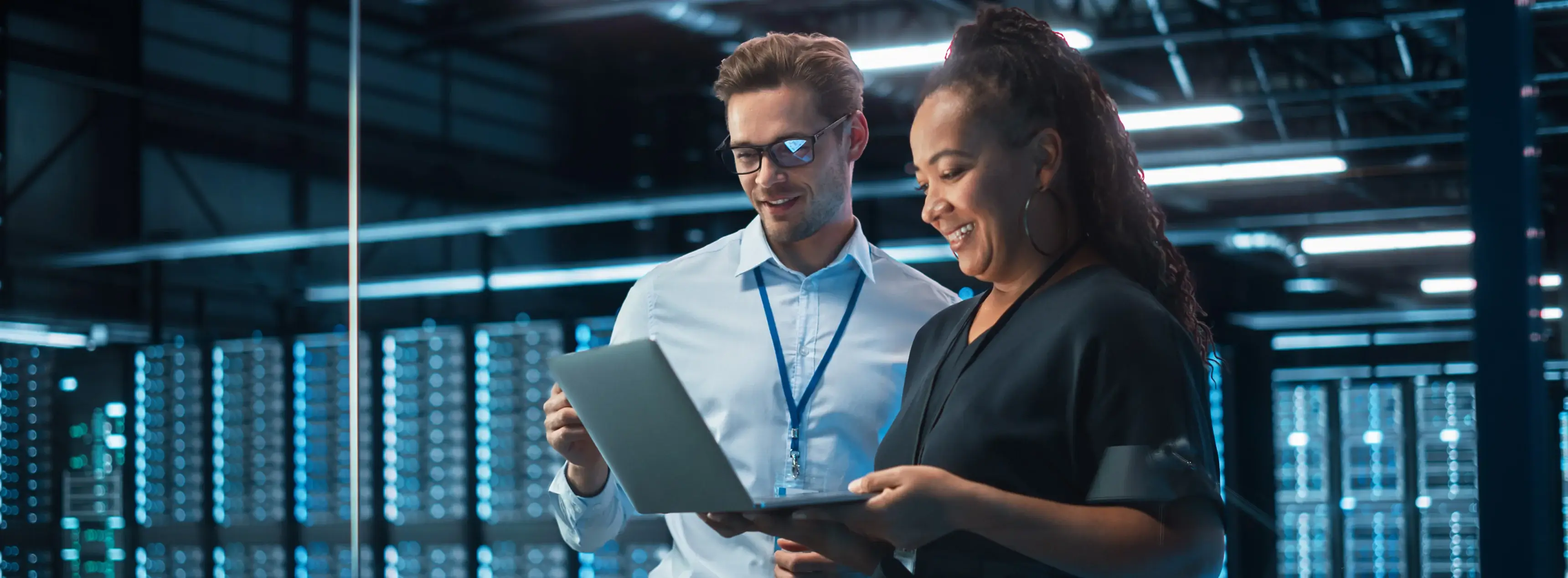 Two people smiling, looking at laptop.